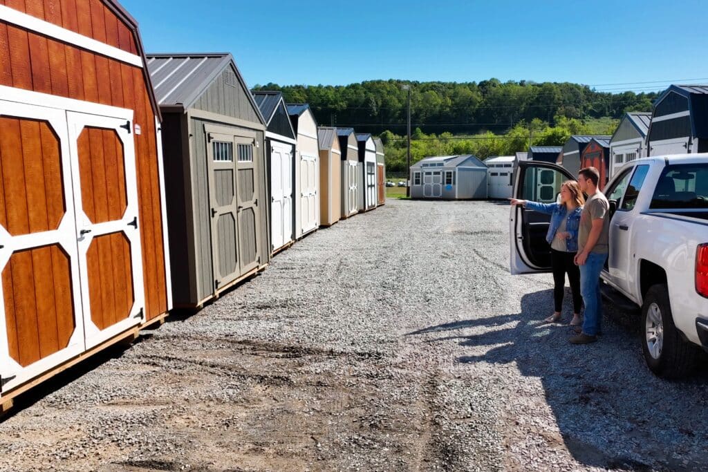 A couple stands on a shed lot looking at sheds
